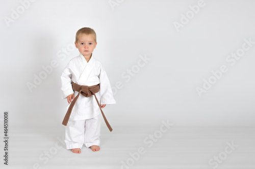 Little baby boy in karate kimono isolated on white background. The concept of martial arts, karate, judo,  sports since childhood, discipline. Defence concept with copy space.