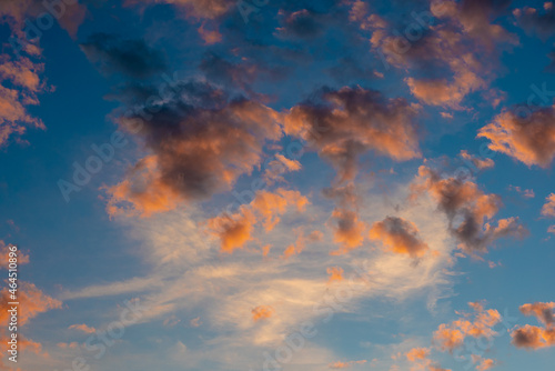 idyllic sunrise cloudscape sky with pink black and white coloured cumulus cloud formation in a pastel blue sky. Sunset or sunrise background image
