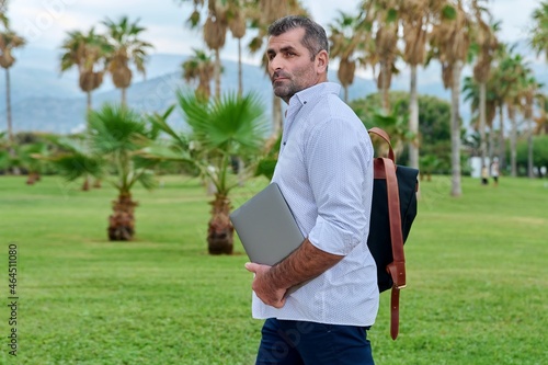 Portrait of serious confident mature man with laptop outdoors