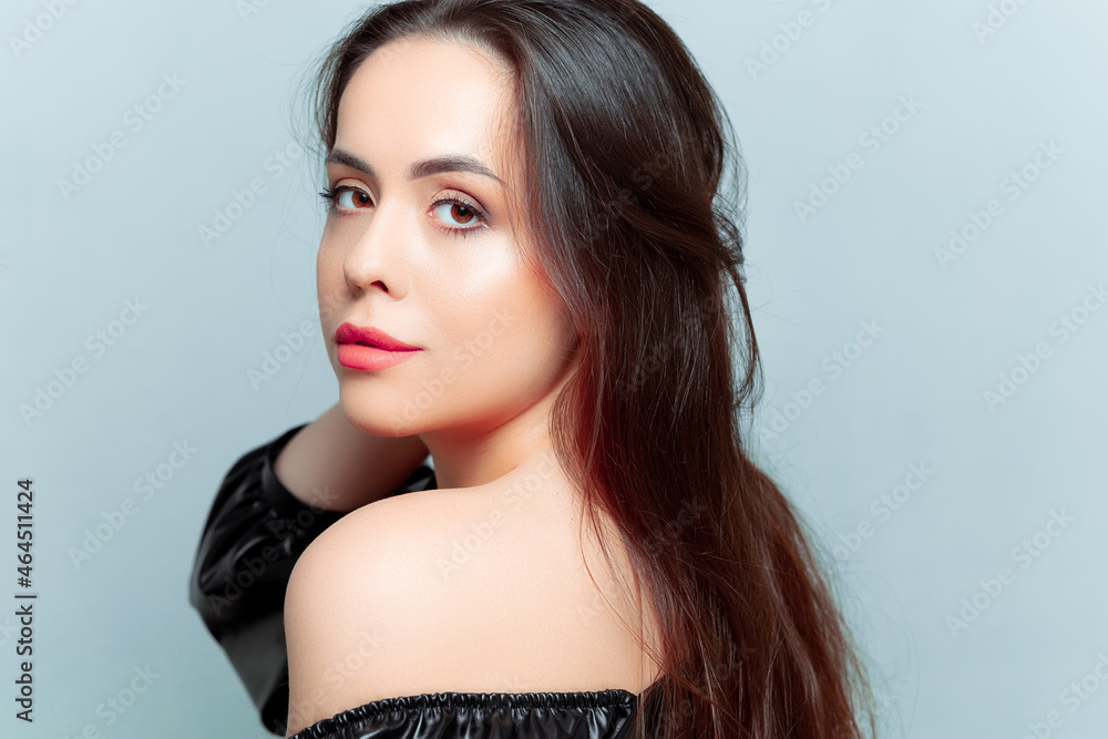Fototapeta premium portraits of a beautiful brunette model who stands sideways and straightens her hair