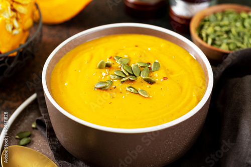 Pumpkin cream soup with seeds on a dark background. Traditional autumn vegetarian dish close-up