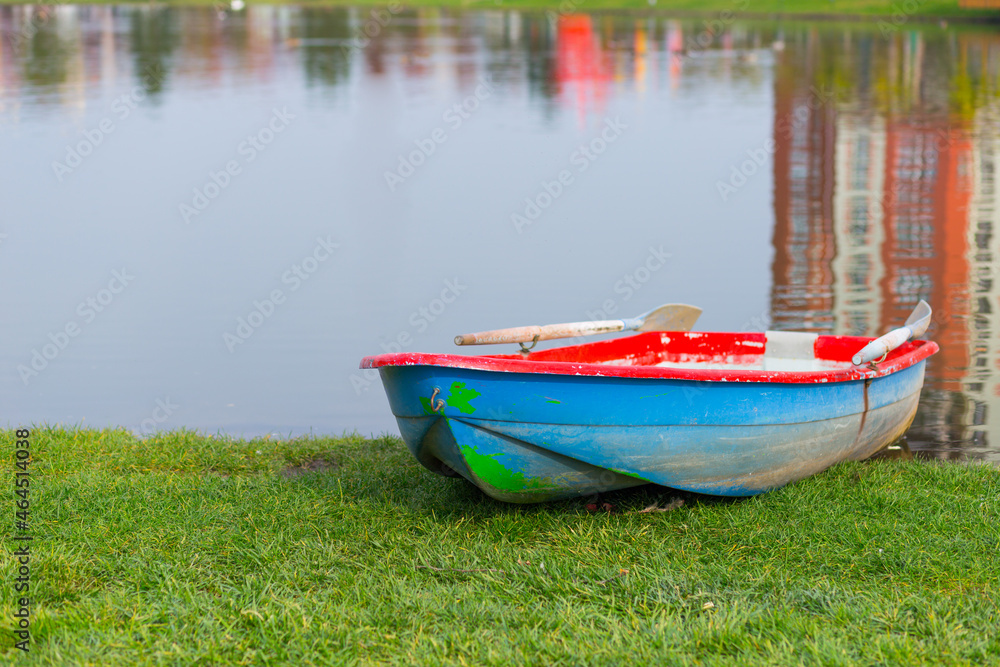Wooden boat on the shore of a transparent lake in the park on a warm clear day Wooden boat on the shore of a transparent lake in the park on a warm clear day