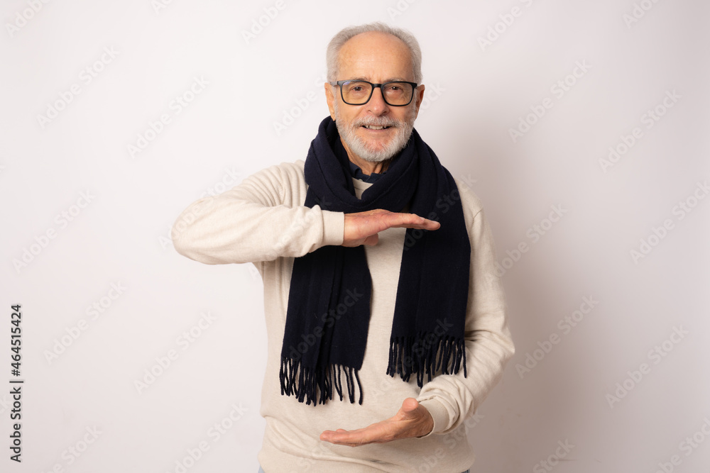 Fototapeta premium Senior man in winter clothing showing product with hands isolated over white background.