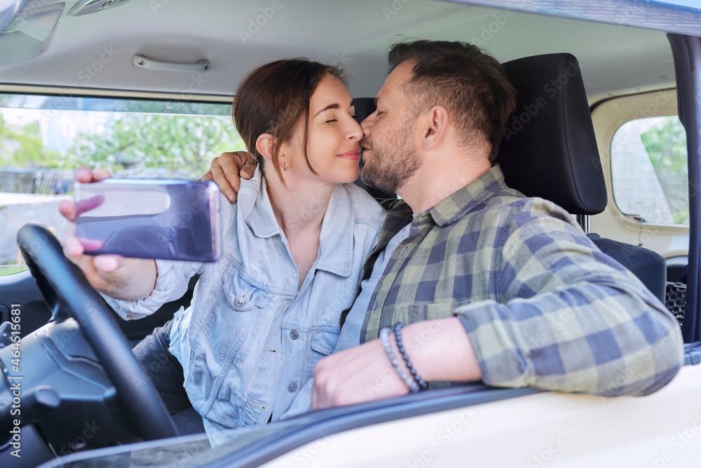 Happy married couple taking selfie photo on smartphone, husband and wife sitting in car Happy married couple taking selfie photo on smartphone, husband and wife sitting in car