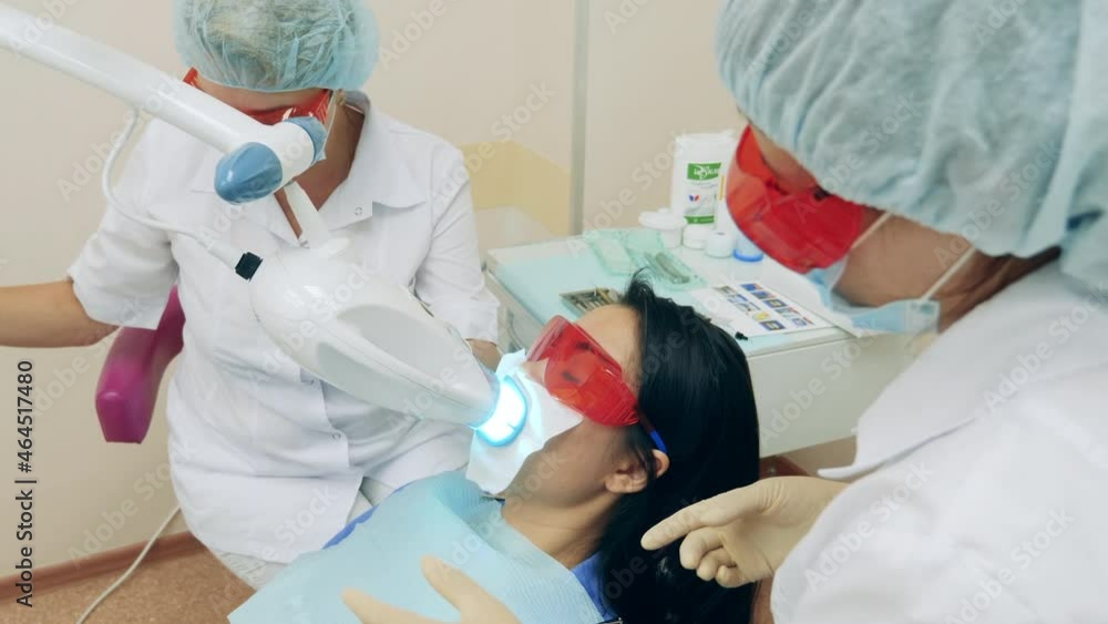 Dentists are carrying out oral hygiene procedure on a woman Dentists are carrying out oral hygiene procedure on a woman