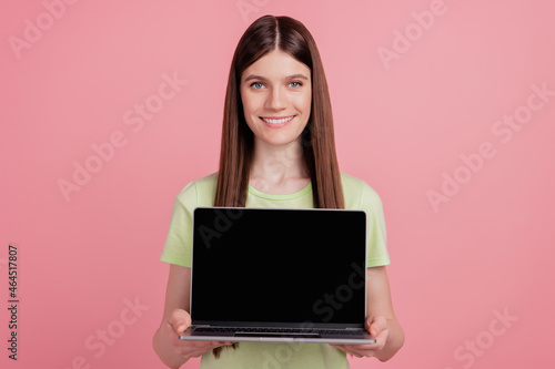 Photo of young cheerful girl hold laptop pc computer with blank empty screen advert advice isolated over pink color background © Tetiana