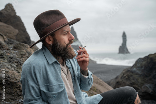 Man smoking weed and blowing puffs of smoke while resting at the foggy beach