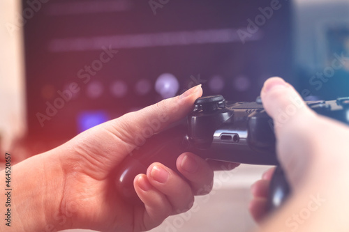 Female gamer hand playing video games on a console with wireless controller at home in cozy room sitting on sofa, close-up view of joystick