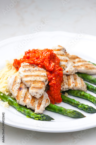 grilled poultry meat with baked red pepper sauce and green asparagus