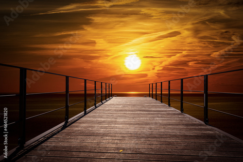 Small empty wooden pier with a beautiful sunset on the horizon over the Mediterranean sea. Italy, Europe.