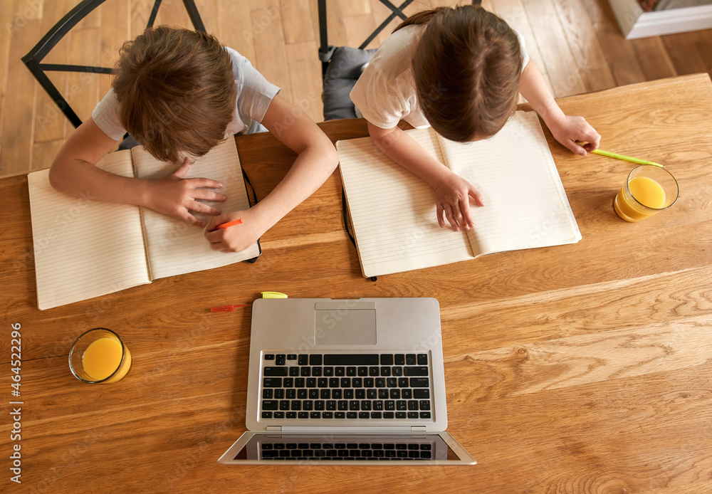 Top down of kids do homework using computer Top down of kids do homework using computer