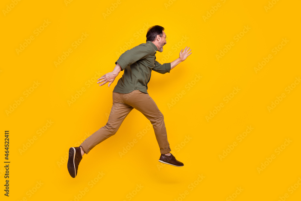 Full length body size profile side view of attractive cheerful man running fast isolated over bright yellow color background