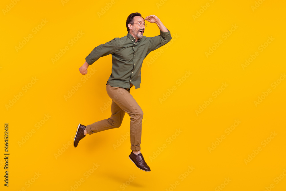 Full length body size view of attractive amazed man jumping running looking far isolated over bright yellow color background Full length body size view of attractive amazed man jumping running looking far isolated over bright yellow color background