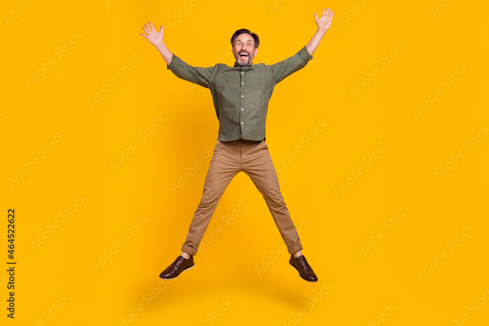Full length body size view of attractive lucky man jumping having fun isolated over vivid yellow color background