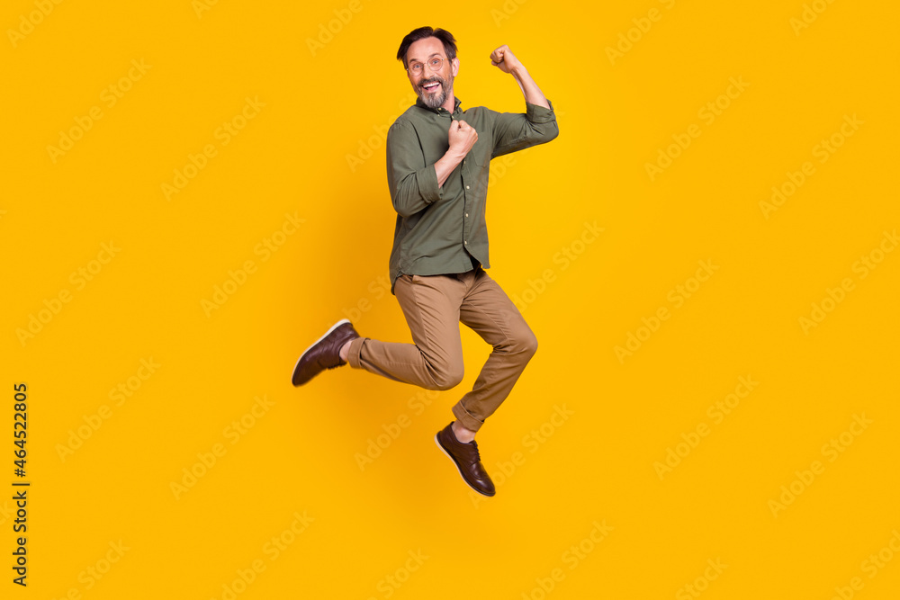 Full length body size view of attractive cheerful lucky man jumping rejoicing isolated over vivid yellow color background