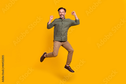 Full length body size view of attractive cheerful man jumping celebrating isolated over vivid yellow color background