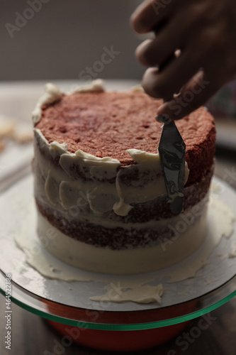 Chef or baker decorating cake with white whipped cream.Soft fokus photo