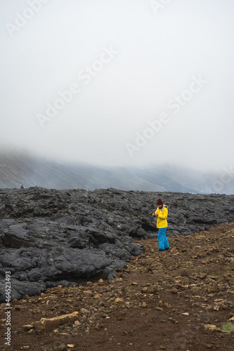 Woman standing on the rocky ground in the mountains in foggy cloudy weather and enjoying