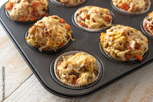 Pizza muffins from yeast dough with tomatoes, vegetables, sausage and cheese in a baking tray fresh from the oven, hearty finger food and party snack