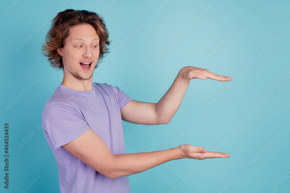 Photo of young excited man happy positive smile show hands measure size length isolated over teal color background Photo of young excited man happy positive smile show hands measure size length isolated over teal color background