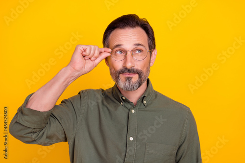 Portrait of attractive minded intellectual man touching specs isolated over bright yellow color background