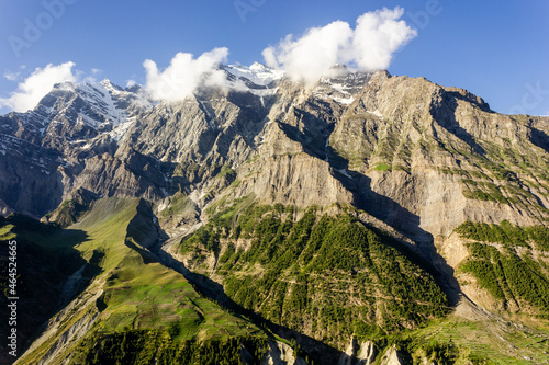 A Himalayan mountain face with green fields and meadows on its steep slopes off the town of Keylong in Lahaul in Himachal Pradesh, India. photo