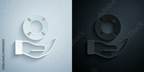 Paper cut Lifebuoy in hand icon isolated on grey and black background. Lifebelt symbol. Paper art style. Vector