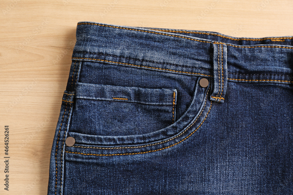 Stylish dark blue jeans on wooden background, closeup of inset pocket Stylish dark blue jeans on wooden background, closeup of inset pocket