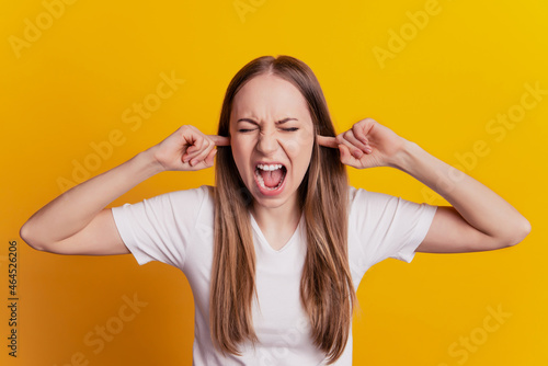 Photo of young girl close ears fingers scream shout stressed noise isolated over yellow color background