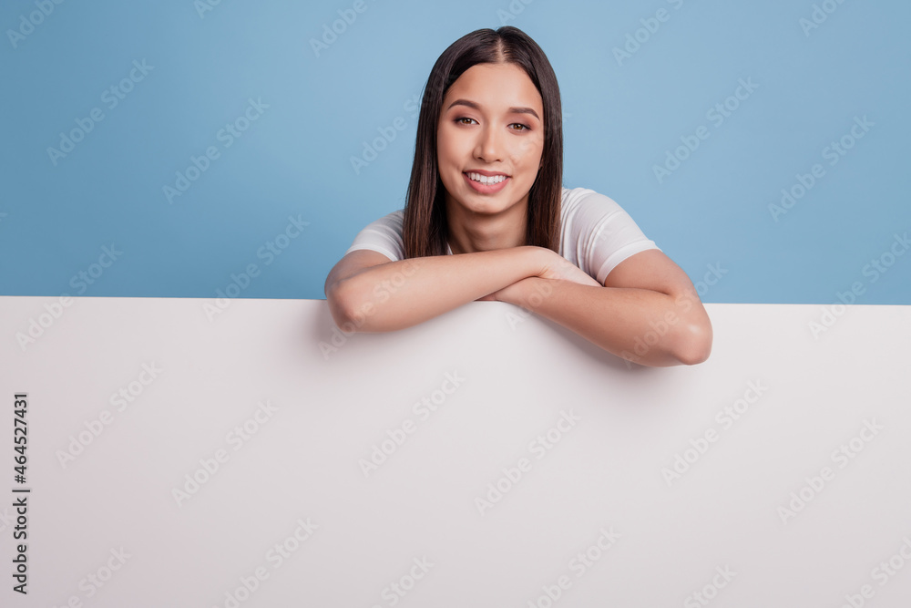 Photo of dreamy relaxed promoter lady lay big white wall banner promo toothy smile on blue background Photo of dreamy relaxed promoter lady lay big white wall banner promo toothy smile on blue background