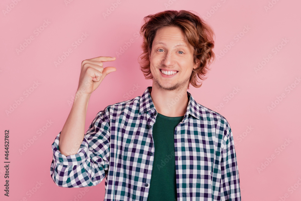 Photo of young man happy positive smile show fingers small little size isolated over pink color background Photo of young man happy positive smile show fingers small little size isolated over pink color background