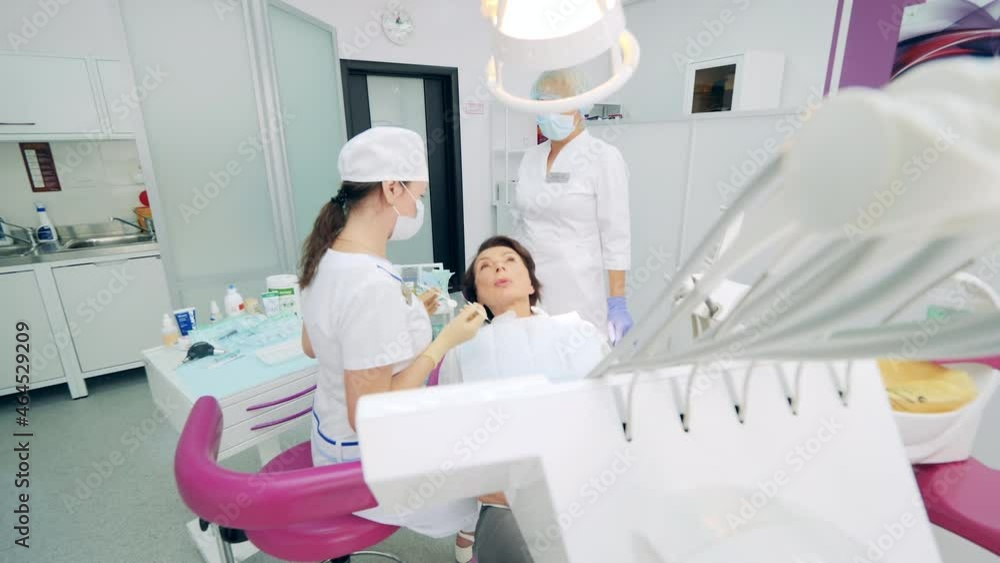 Female patient is talking to dentists while being in a chair Female patient is talking to dentists while being in a chair