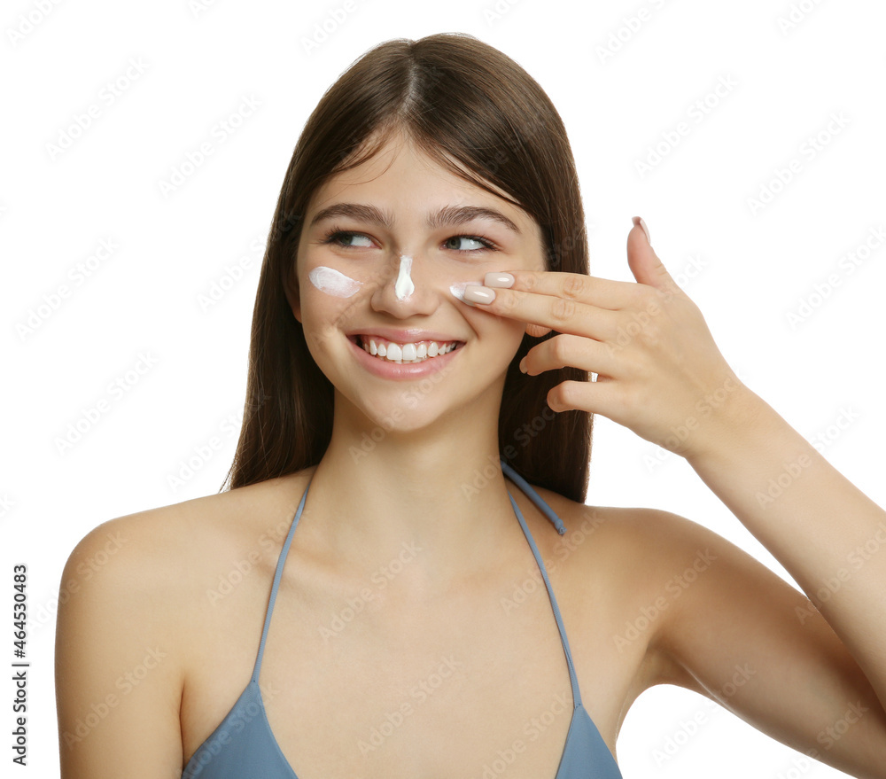 Teenage girl applying sun protection cream on her face against white background Teenage girl applying sun protection cream on her face against white background