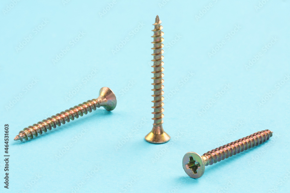 Three screws on a blue background, one standing and two diagonally Three screws on a blue background, one standing and two diagonally