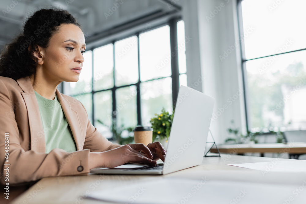 concentrated african american businesswoman typing on laptop in office concentrated african american businesswoman typing on laptop in office