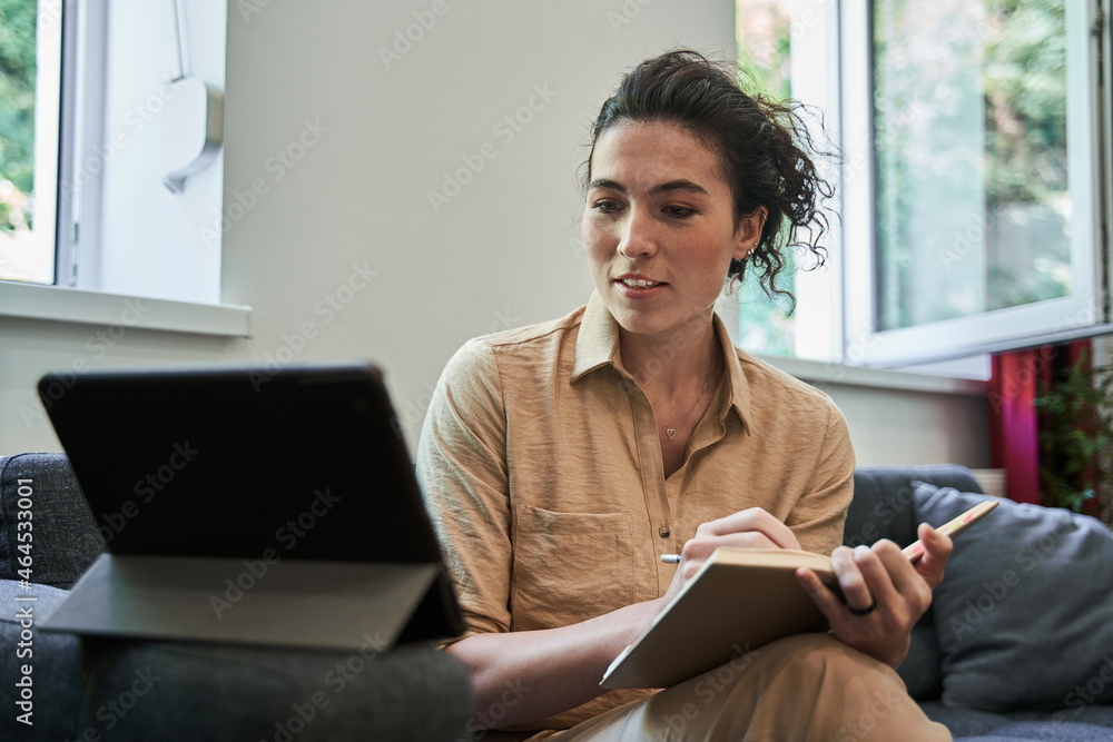 Female psychologist making notes with pleasure smile while holding video call Female psychologist making notes with pleasure smile while holding video call