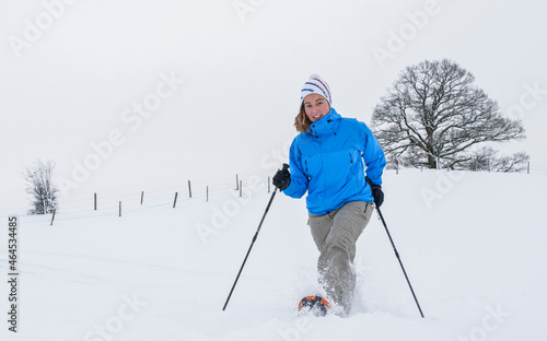 Junge Frau ist mit Schneeschuhen unterwegs in winterlicher Landschaft