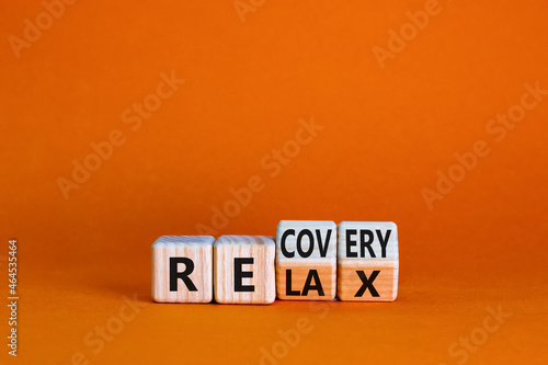 Relax and recovery symbol. Businessman turned cubes and changed the word 'relax' to 'recovery'. Beautiful orange table, orange background. Business, relax and recovery concept. Copy space.