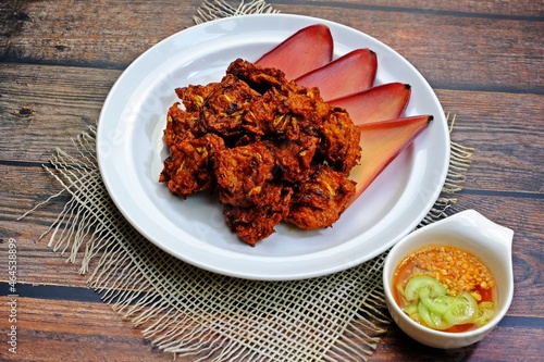 Fried banana blossom patty (Tod Mun Hua Plee) in white plate on wooden table. Authentic Thai food. photo