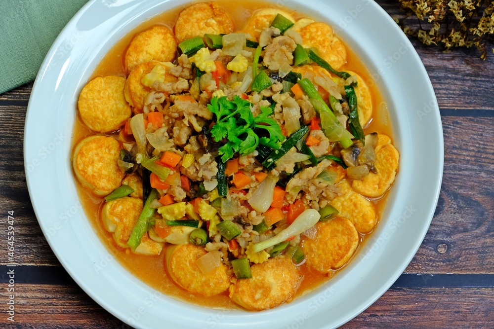 Deep fried tofu with gravy sauce (Tao Hoo Song Kreung) in white plate on wooden table, Healthy dish. Deep fried tofu with gravy sauce (Tao Hoo Song Kreung) in white plate on wooden table, Healthy dish.
