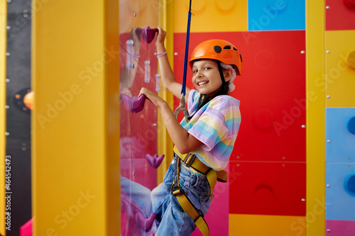 Little girl in helmet poses on climbing wall photo