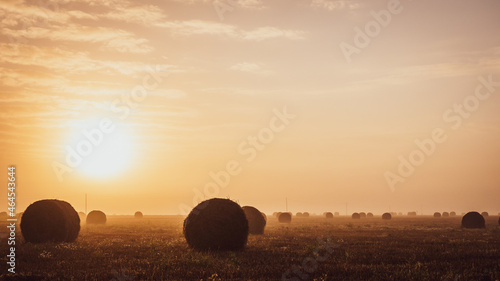 Magnifique lever de soleil au dessus d'un champ après la moisson avec ses ballots de paille