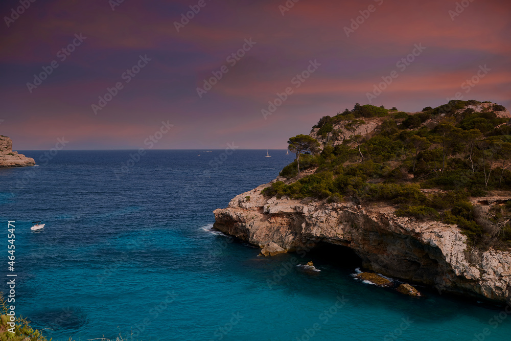 Turquoise beach cliffs with orange sunrise or sunset skies