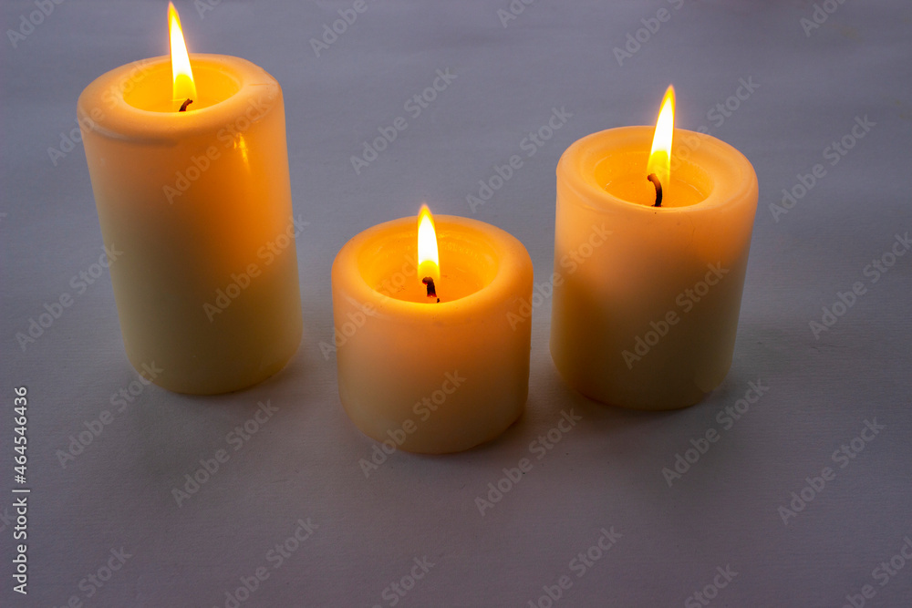 Three white candles burning on gray gradient background. Top view. Three white candles burning on gray gradient background. Top view.