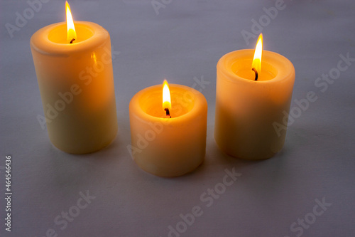Three white candles burning on gray gradient background. Top view. 