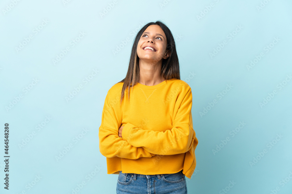 Caucasian girl isolated on blue background looking up while smiling Caucasian girl isolated on blue background looking up while smiling