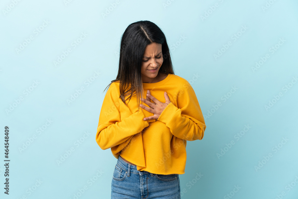 Caucasian girl isolated on blue background having a pain in the heart Caucasian girl isolated on blue background having a pain in the heart