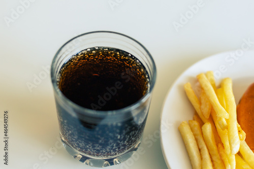 French fries in the white dish with souse and soda in glass
