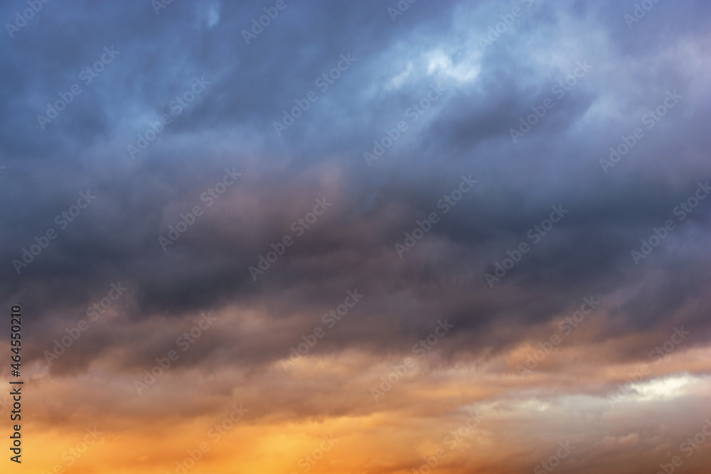 Gray rain clouds in the rays of the sun at sunset. Thunderclouds in dark blue color