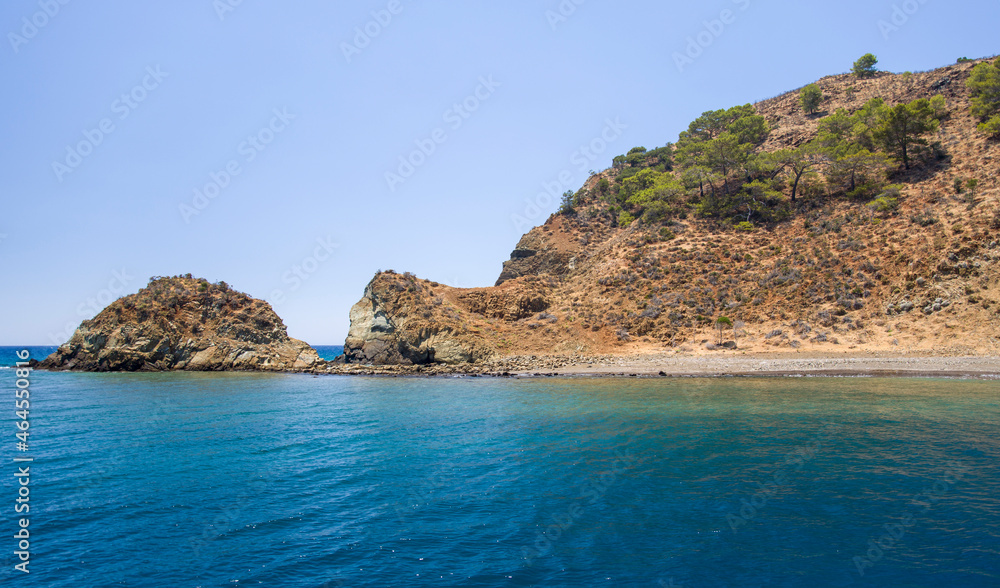 Rocky island beach with turquoise calm water and clear blue sky